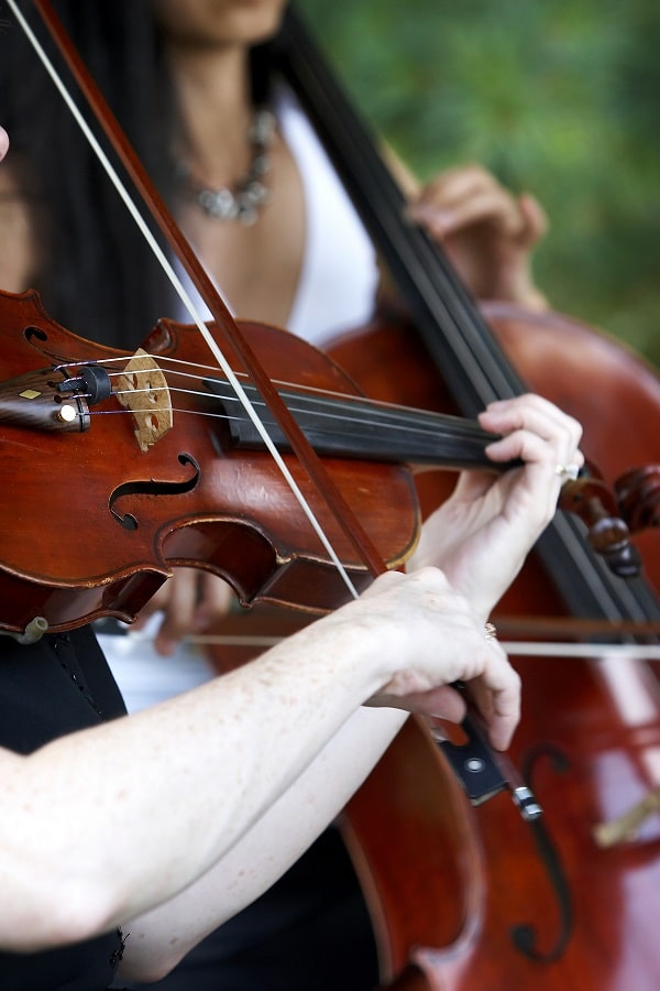 shutterstock_1613817 People playing stringed instruments in a well lit outdoor area.